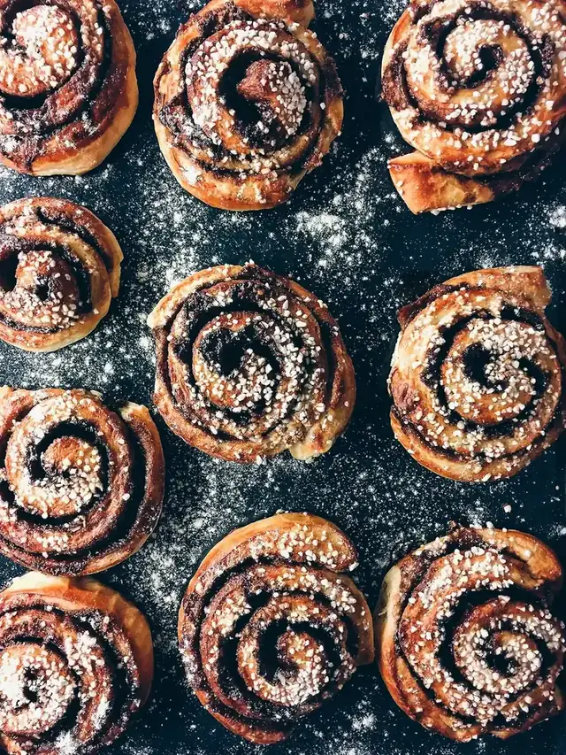 Cinnamon buns dusted with sugar on a dark tray