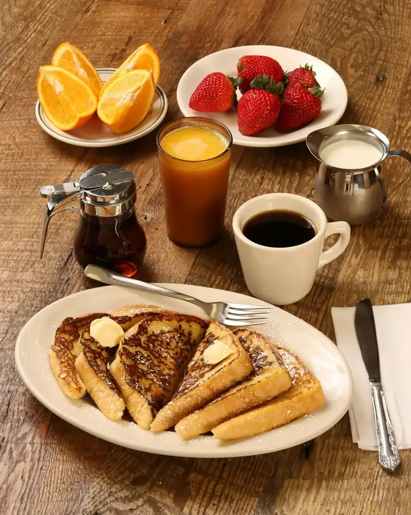 Pancakes with strawberries and oranges on a wooden table